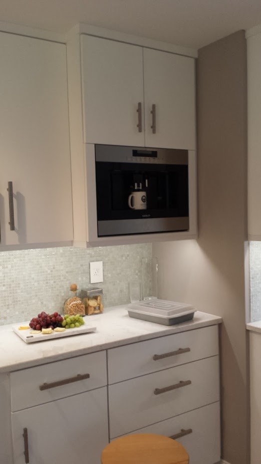 Enclosed kitchen - small transitional galley medium tone wood floor enclosed kitchen idea with an undermount sink, flat-panel cabinets, white cabinets, quartz countertops, white backsplash, mosaic tile backsplash, stainless steel appliances and a peninsula