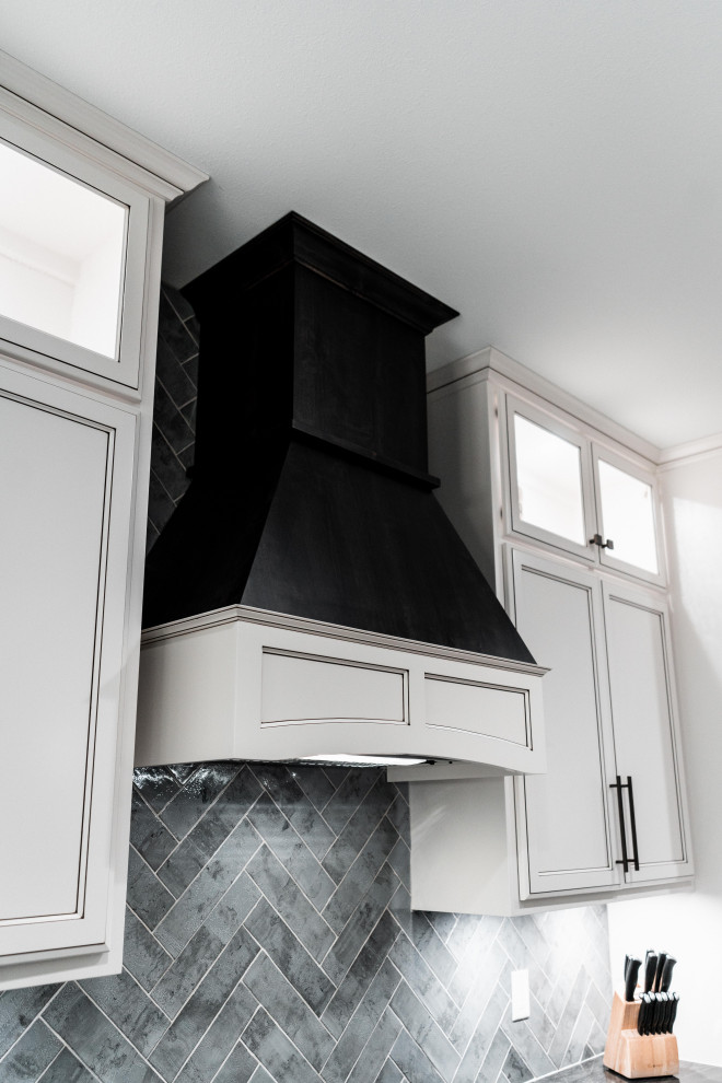 Open concept kitchen - huge transitional l-shaped laminate floor, gray floor and tray ceiling open concept kitchen idea with an undermount sink, flat-panel cabinets, white cabinets, quartz countertops, gray backsplash, ceramic backsplash, black appliances and an island