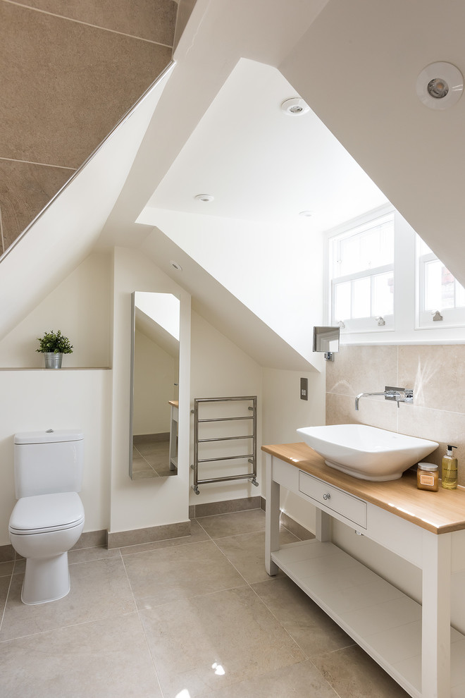 Design ideas for a mid-sized traditional kids bathroom in London with furniture-like cabinets, white cabinets, an open shower, a two-piece toilet, beige tile, travertine, beige walls, travertine floors, a vessel sink, wood benchtops, beige floor and an open shower.
