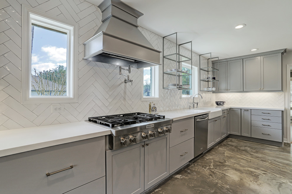 This is an example of a mid-sized traditional galley open plan kitchen in Houston with a farmhouse sink, recessed-panel cabinets, grey cabinets, granite benchtops, white splashback, subway tile splashback, stainless steel appliances, cement tiles, with island, grey floor and white benchtop.