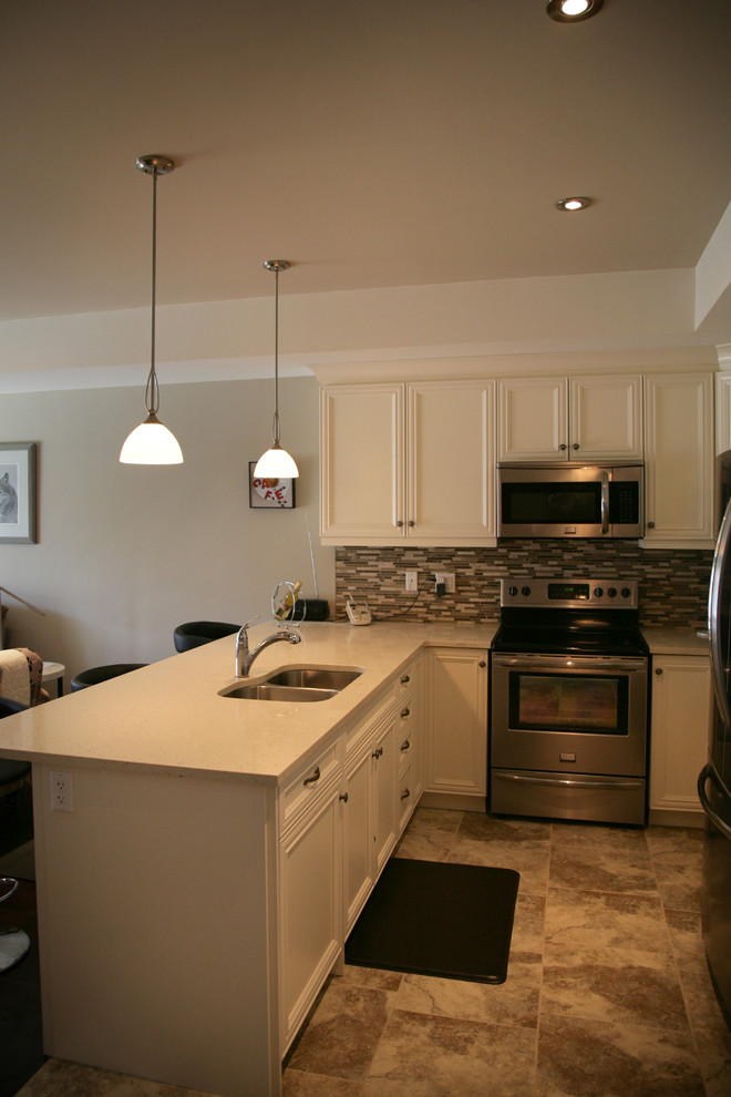 Eat-in kitchen - small transitional u-shaped porcelain tile eat-in kitchen idea in Toronto with an undermount sink, flat-panel cabinets, white cabinets, solid surface countertops, beige backsplash, glass tile backsplash, stainless steel appliances and an island