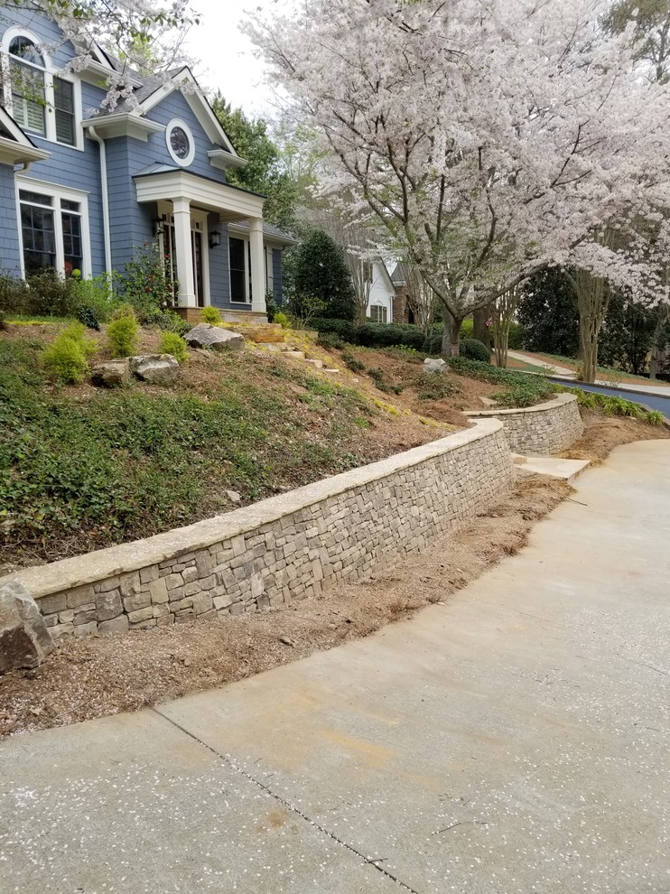 This is an example of a large country sloped driveway in Atlanta with a retaining wall and river rock.