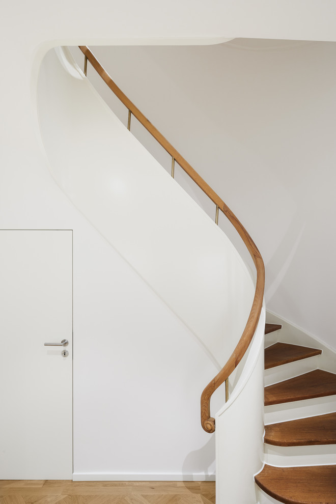 This is an example of an expansive classic wood curved mixed railing staircase in Cologne with wood risers.