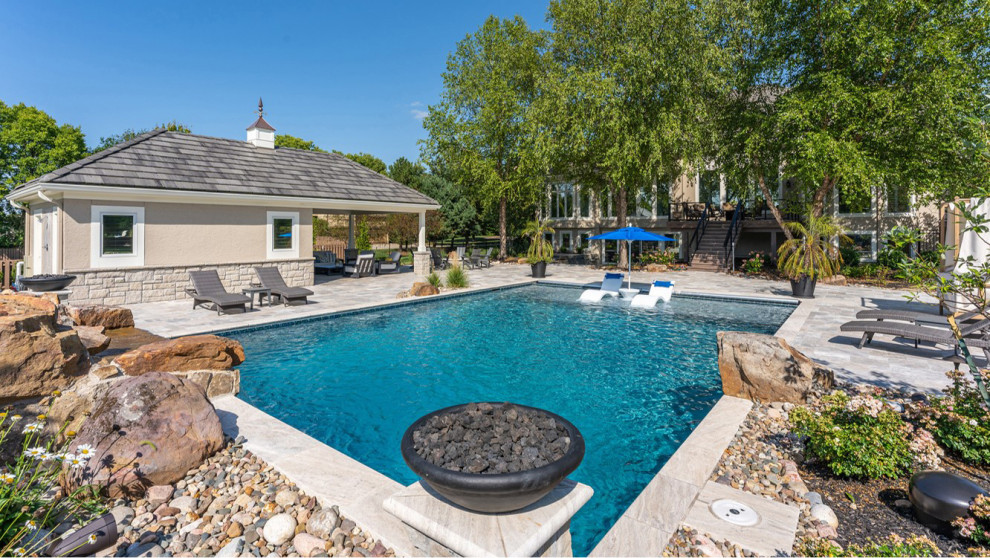 Mid-sized transitional backyard rectangular pool in Kansas City with a pool house and natural stone pavers.