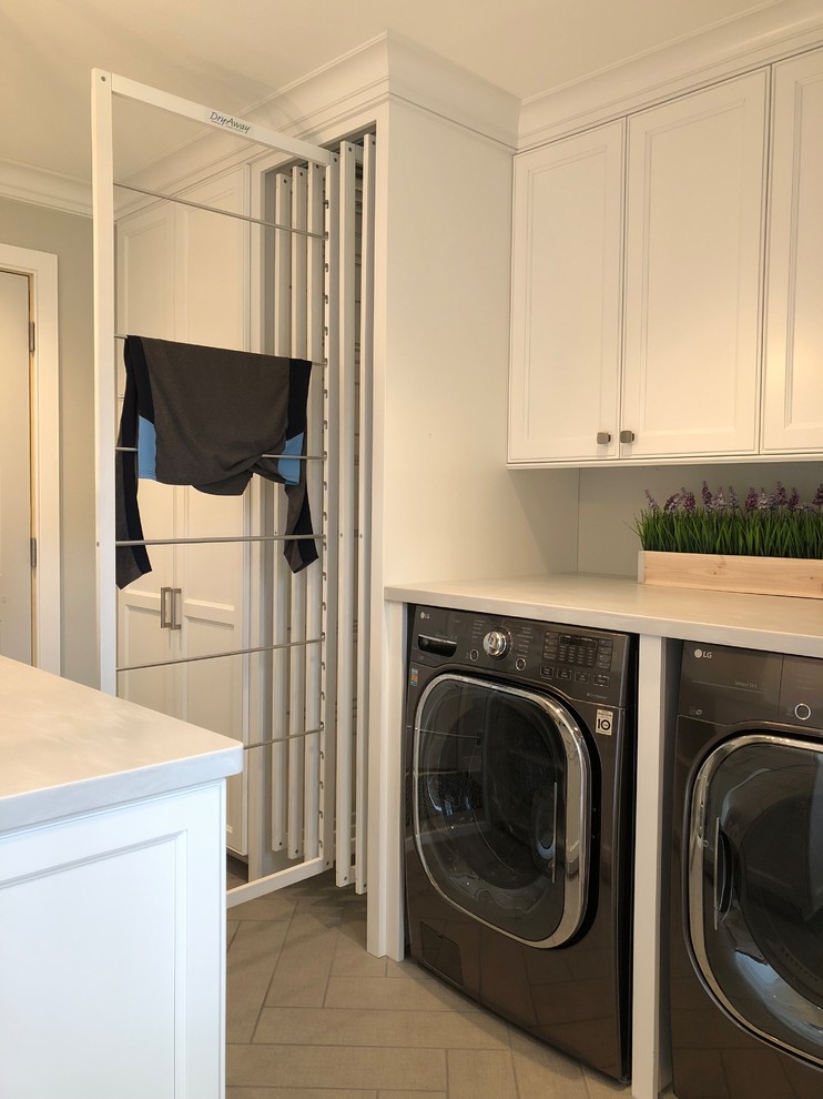 Inspiration for a mid-sized transitional galley ceramic tile and brown floor utility room remodel in Milwaukee with a farmhouse sink, recessed-panel cabinets, white cabinets, gray walls, a concealed washer/dryer and gray countertops