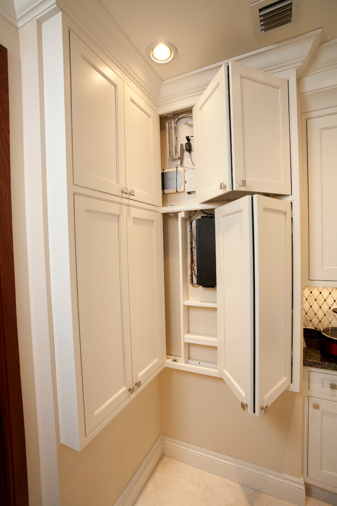 This is an example of a small transitional u-shaped kitchen pantry in Orlando with an undermount sink, white cabinets, granite benchtops, white splashback, mosaic tile splashback, stainless steel appliances, marble floors and no island.