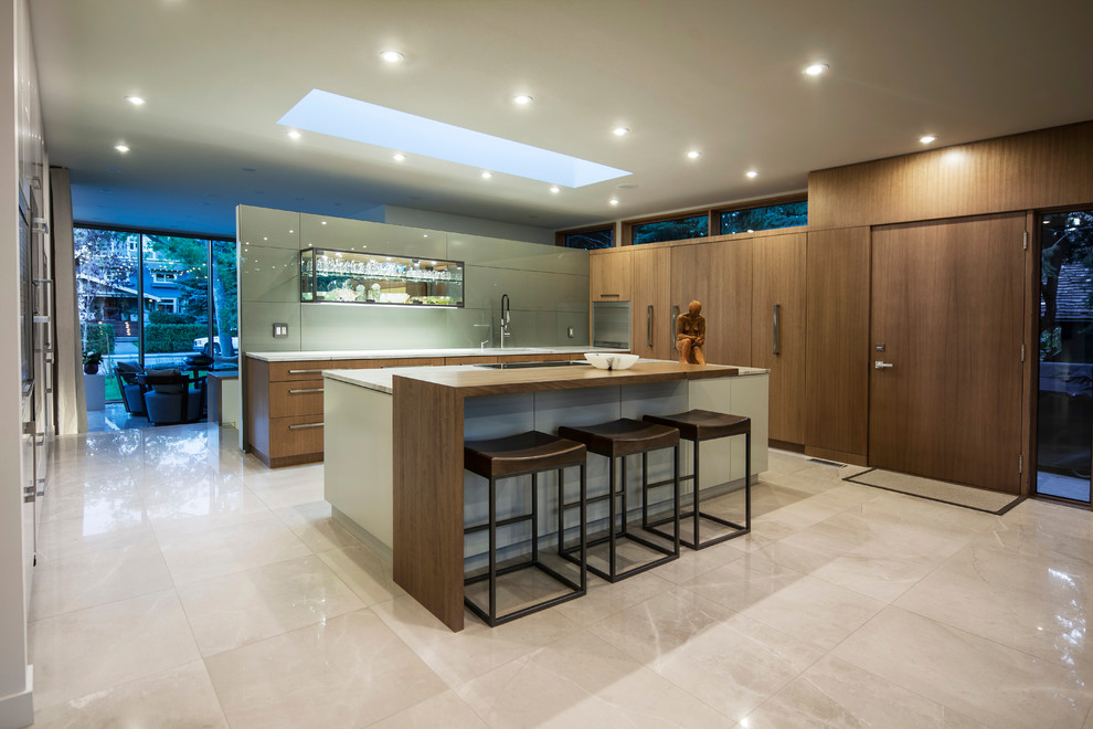 Inspiration for a large contemporary l-shaped kitchen in Calgary with flat-panel cabinets, medium wood cabinets, granite benchtops, grey splashback, glass sheet splashback, panelled appliances, marble floors, with island and an undermount sink.