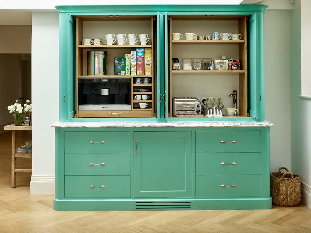 Photo of a country kitchen pantry in Kent with flat-panel cabinets, green cabinets and light hardwood floors.