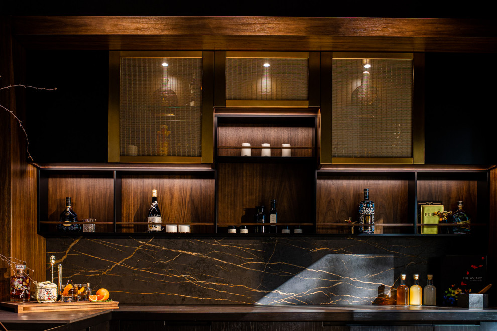 Inspiration for a small modern l-shaped home bar in San Francisco with no sink, glass-front cabinets, black cabinets, solid surface benchtops, black splashback, engineered quartz splashback and black benchtop.