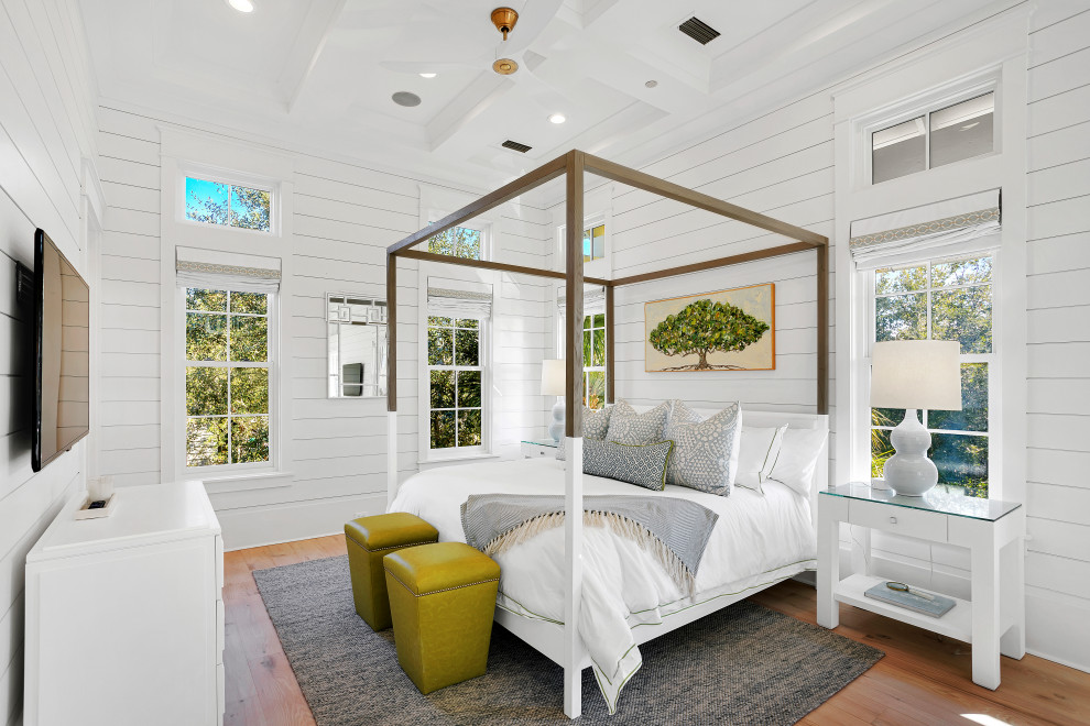 This is an example of an expansive beach style guest bedroom in Other with white walls, light hardwood floors, beige floor, coffered and planked wall panelling.