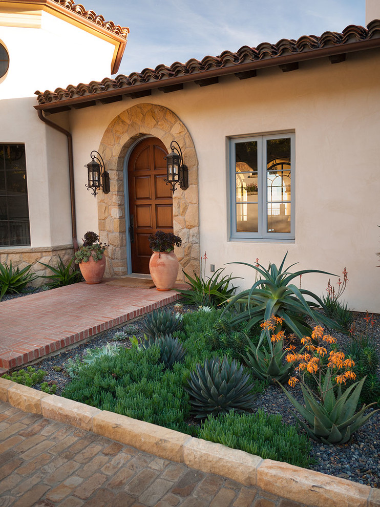 Mediterranean front yard xeriscape in Santa Barbara with natural stone pavers.