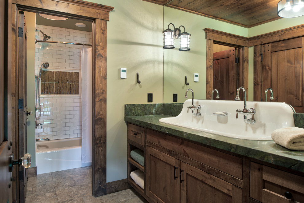 Photo of a mid-sized country bathroom in Minneapolis with flat-panel cabinets, dark wood cabinets, an alcove tub, a shower/bathtub combo, a two-piece toilet, white tile, subway tile, green walls, ceramic floors, a drop-in sink, granite benchtops, brown floor and a shower curtain.