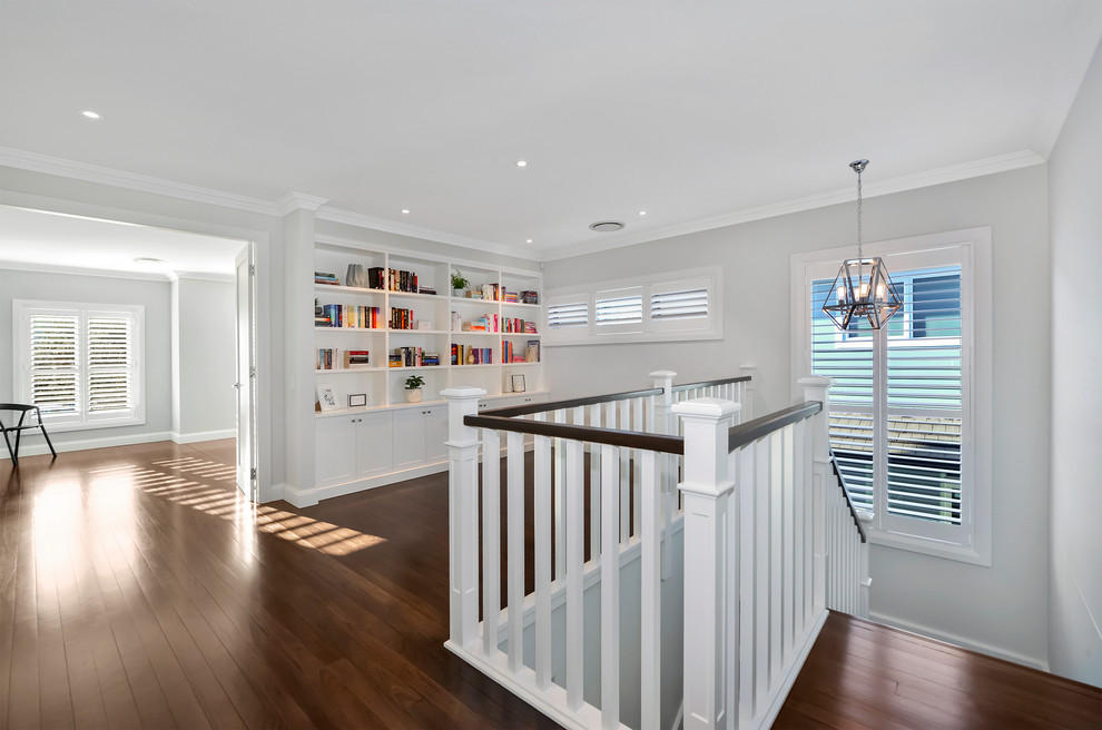 This is an example of a large contemporary home office in Sydney with a library, brown floor, grey walls and dark hardwood floors.