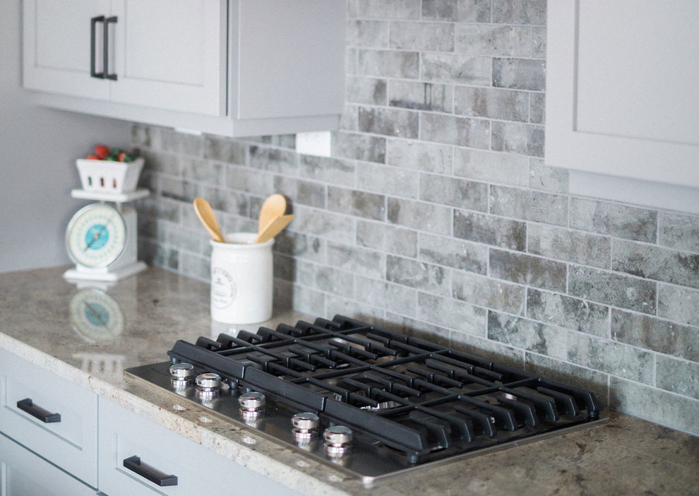 Inspiration for a large transitional kitchen remodel with a farmhouse sink, granite countertops, gray backsplash, stainless steel appliances and an island