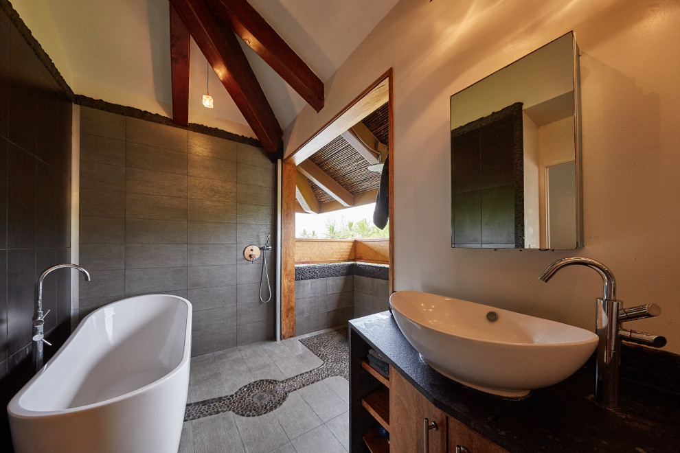 This is an example of a mid-sized modern master bathroom in Hawaii with an open shower, gray tile, beige walls, cement tiles, grey floor, an open shower, black benchtops, a single vanity, a built-in vanity and exposed beam.