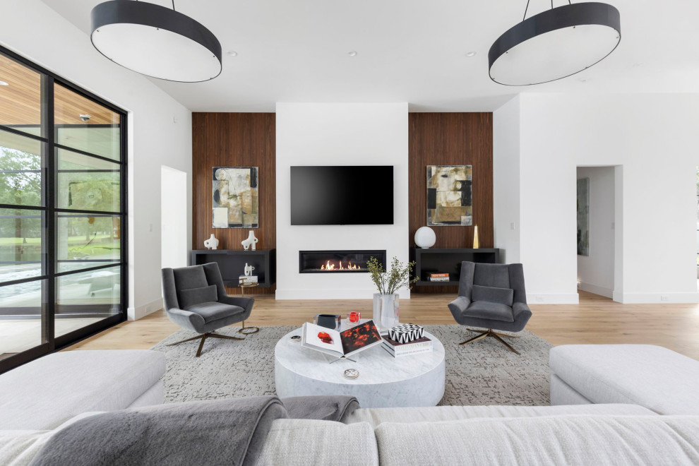 Foto de sala de estar abierta moderna grande con paredes blancas, suelo de madera clara, chimenea lineal, televisor colgado en la pared y suelo beige