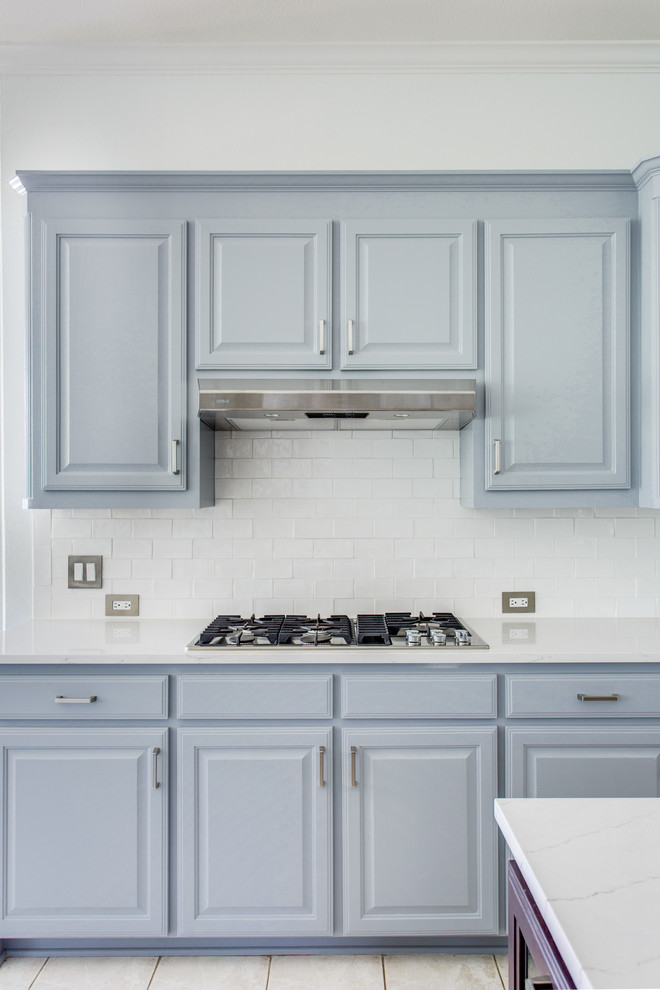 Inspiration for a mid-sized transitional u-shaped eat-in kitchen in Dallas with an undermount sink, raised-panel cabinets, grey cabinets, quartz benchtops, white splashback, subway tile splashback, black appliances, ceramic floors, with island, grey floor and white benchtop.
