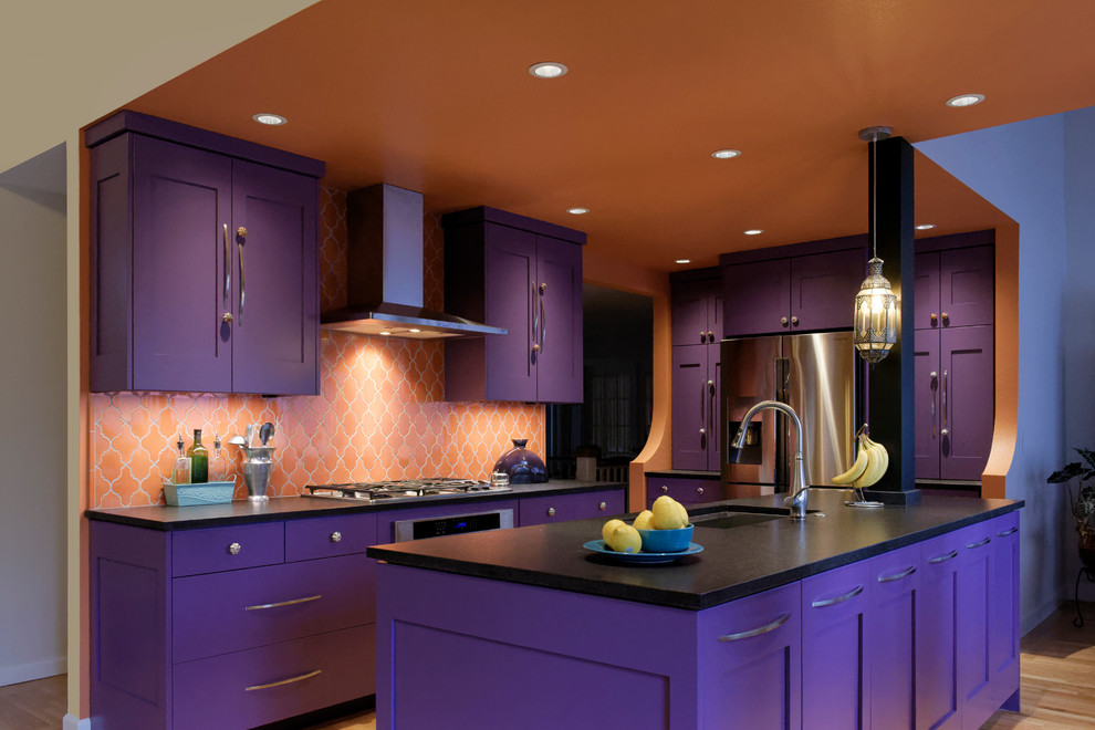 Design ideas for a large eclectic galley eat-in kitchen in Portland with an undermount sink, shaker cabinets, purple cabinets, solid surface benchtops, orange splashback, ceramic splashback, stainless steel appliances, light hardwood floors and with island.