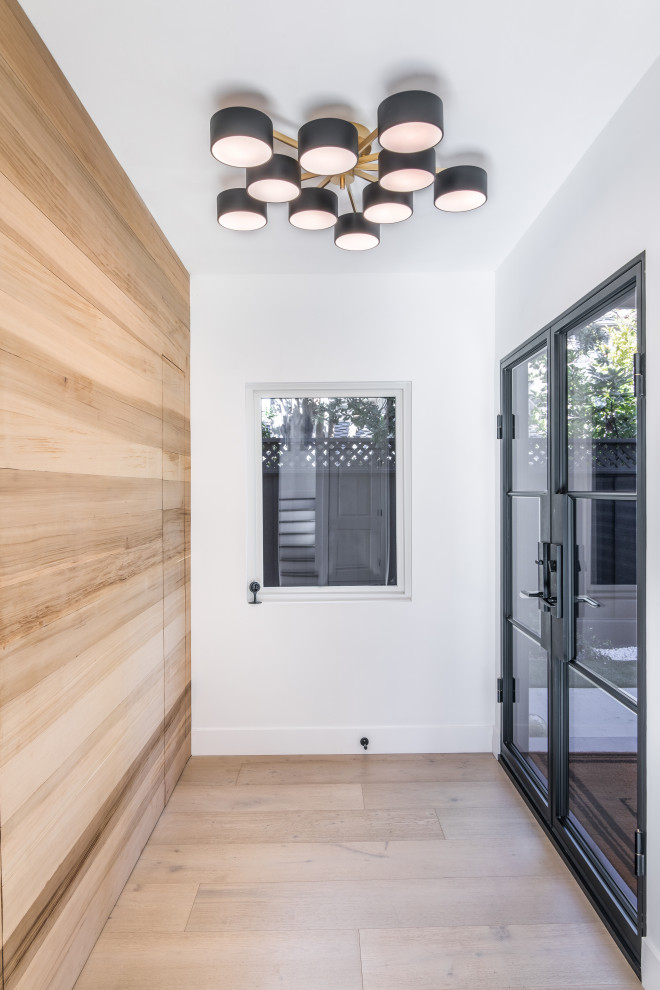 Imagen de distribuidor minimalista grande con paredes blancas, suelo de madera clara, puerta doble, puerta negra, suelo blanco y machihembrado