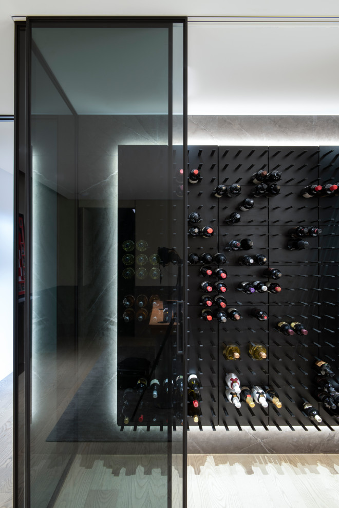 This is an example of a medium sized contemporary wine cellar in Sydney with medium hardwood flooring, storage racks and feature lighting.