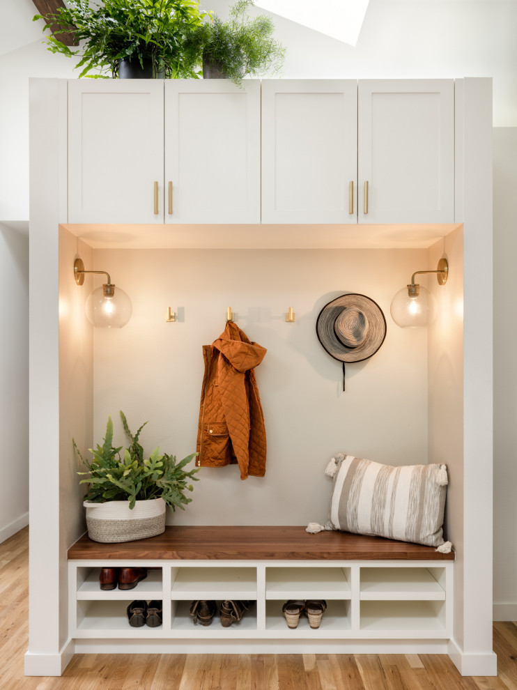 This is an example of a small scandinavian mudroom in Seattle with grey walls, light hardwood floors and vaulted.