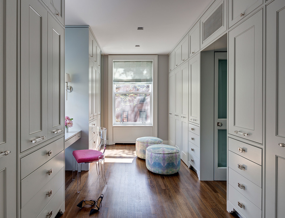 Inspiration for a large transitional women's dressing room in New York with medium hardwood floors, beaded inset cabinets and grey cabinets.