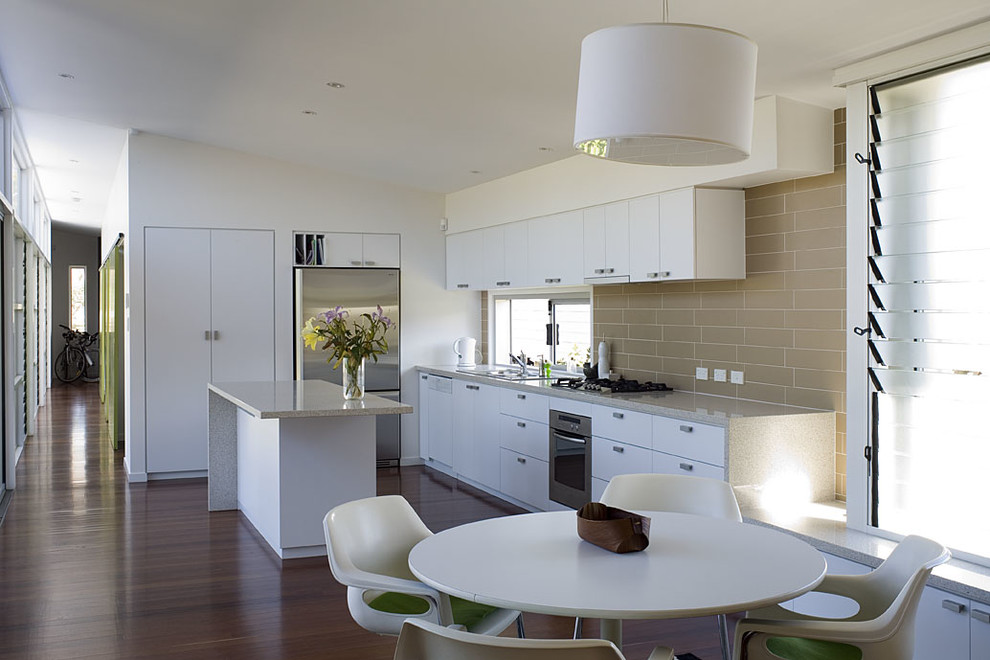 This is an example of a contemporary l-shaped eat-in kitchen in Brisbane with ceramic splashback and with island.