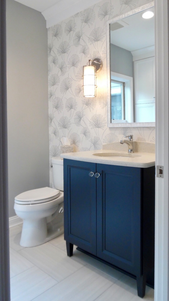 Exemple d'un WC et toilettes chic de taille moyenne avec un placard à porte plane, des portes de placard bleues, un sol en carrelage de porcelaine, un plan de toilette en quartz modifié, un sol blanc, un plan de toilette blanc, meuble-lavabo sur pied et du papier peint.