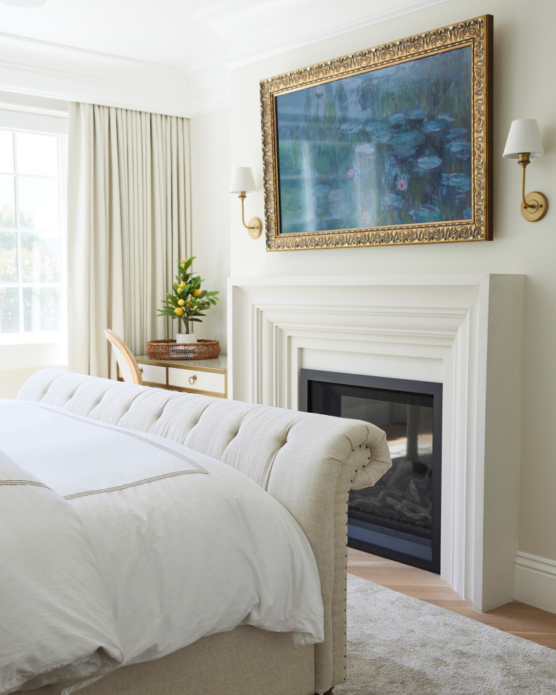 Cette image montre une grande chambre parentale traditionnelle avec un mur blanc, parquet clair, une cheminée standard et un manteau de cheminée en béton.
