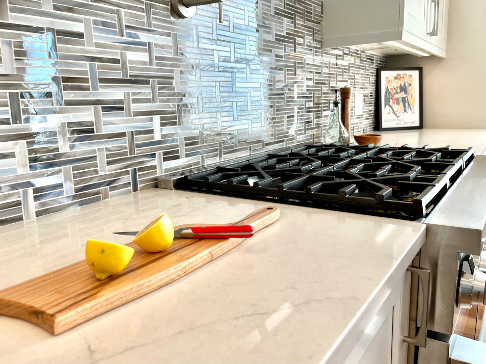 Inspiration for a transitional single-wall vinyl floor, brown floor and vaulted ceiling eat-in kitchen remodel with an undermount sink, shaker cabinets, white cabinets, quartz countertops, blue backsplash, glass sheet backsplash, stainless steel appliances, an island and gray countertops