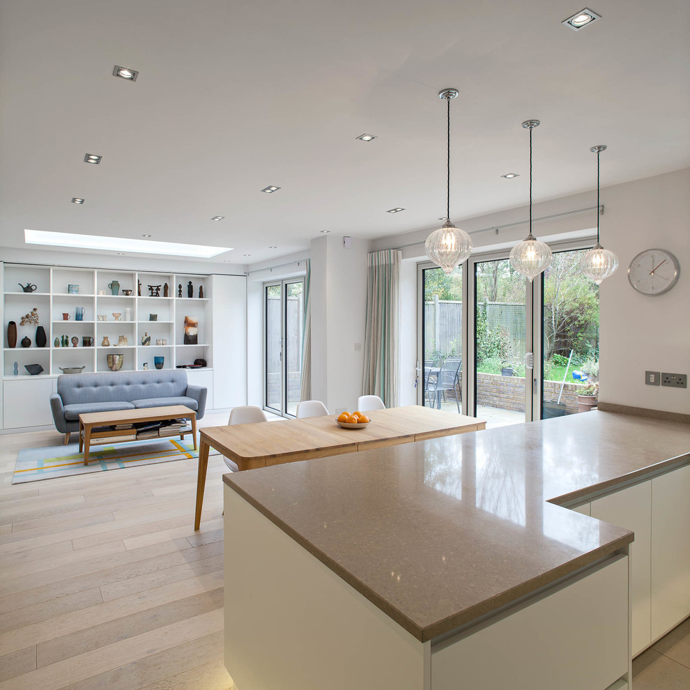 This is an example of a large contemporary kitchen in Hertfordshire with solid surface benchtops and light hardwood floors.
