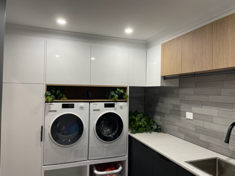 Foto de cuarto de lavado en L actual de tamaño medio con fregadero encastrado, armarios con paneles lisos, encimera de laminado y lavadora y secadora juntas