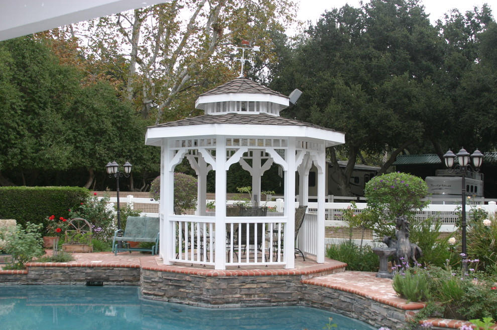 This is an example of a mid-sized traditional backyard patio in Los Angeles with natural stone pavers and a gazebo/cabana.