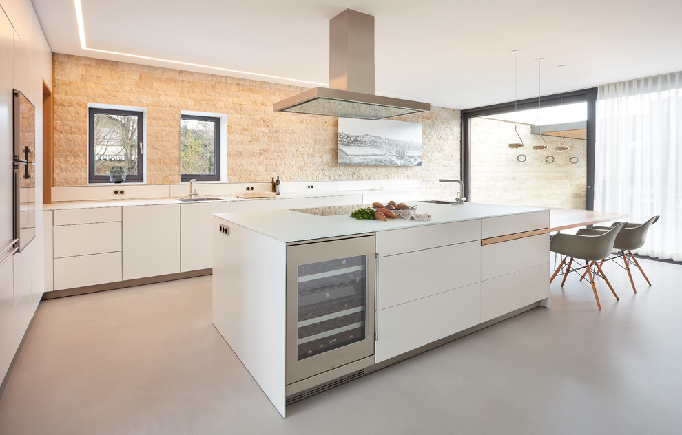 This is an example of a large contemporary l-shaped separate kitchen in Stuttgart with an integrated sink, flat-panel cabinets, white cabinets, beige splashback, stone slab splashback, stainless steel appliances, vinyl floors, with island, grey floor and white benchtop.