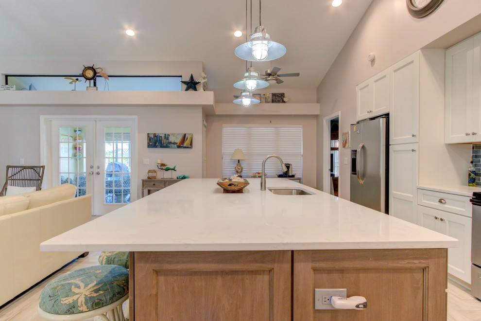 Example of a large single-wall porcelain tile and white floor open concept kitchen design with an undermount sink, shaker cabinets, white cabinets, quartz countertops, blue backsplash, stainless steel appliances, an island and white countertops