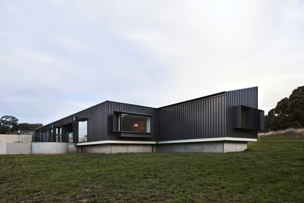 This is an example of a large modern one-storey black house exterior in Other with metal siding and a black roof.