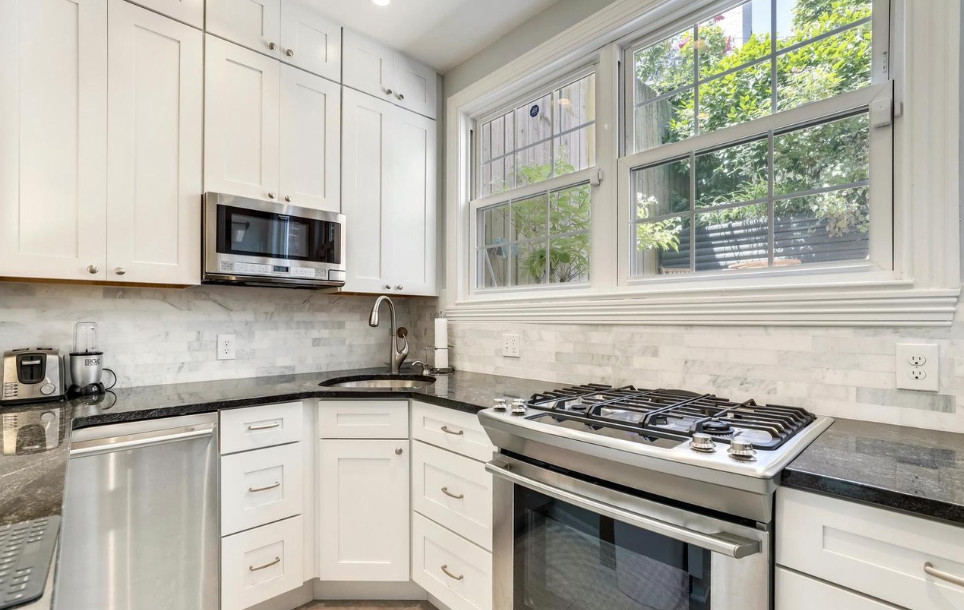 Mid-sized transitional u-shaped medium tone wood floor and brown floor enclosed kitchen photo in DC Metro with an undermount sink, recessed-panel cabinets, white cabinets, granite countertops, white backsplash, marble backsplash, stainless steel appliances, a peninsula and black countertops