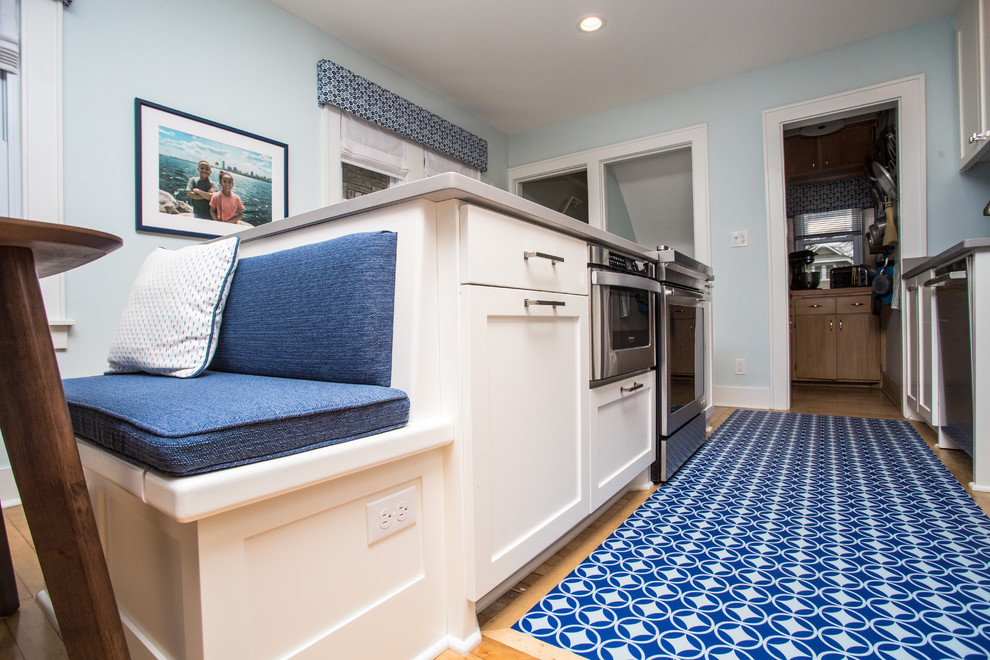 Example of a mid-sized transitional galley light wood floor enclosed kitchen design in Milwaukee with an undermount sink, shaker cabinets, medium tone wood cabinets, quartz countertops, blue backsplash, ceramic backsplash, stainless steel appliances and an island