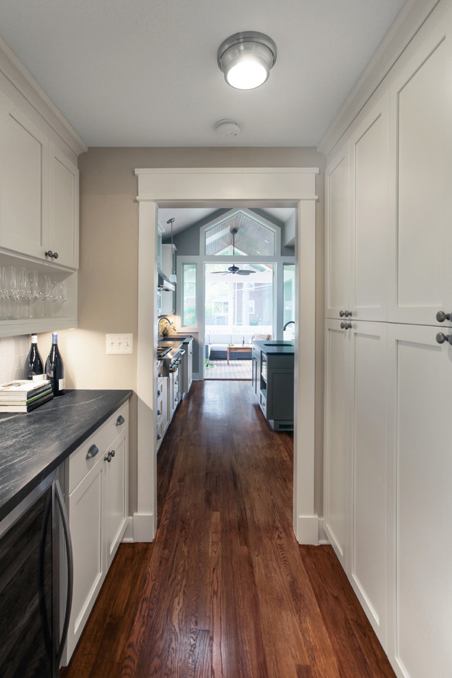 Inspiration for a mid-sized transitional galley dark wood floor home design remodel in DC Metro with no sink, recessed-panel cabinets, white cabinets, soapstone countertops, gray backsplash and subway tile backsplash