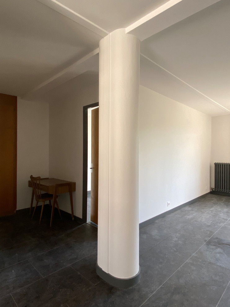 Cette image montre une salle de séjour design de taille moyenne et ouverte avec un mur blanc, un sol en vinyl, aucune cheminée et un sol noir.