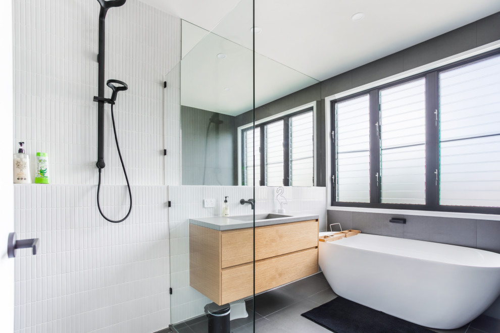 Design ideas for a contemporary bathroom in Gold Coast - Tweed with flat-panel cabinets, light wood cabinets, a freestanding tub, a corner shower, white tile, an integrated sink, grey floor, grey benchtops, a single vanity and a floating vanity.