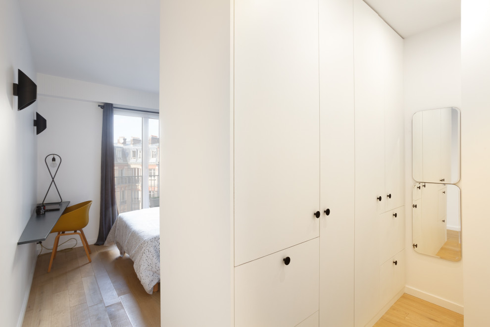 Ejemplo de armario vestidor unisex moderno de tamaño medio con armarios con paneles lisos, puertas de armario blancas, suelo de madera clara y suelo beige