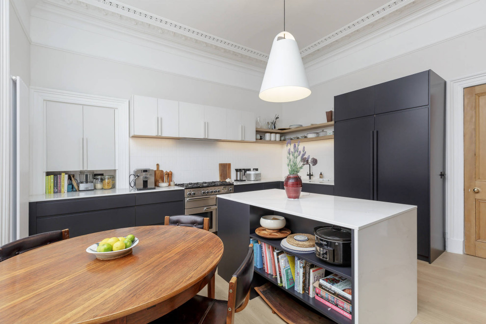 Mid-sized contemporary l-shaped eat-in kitchen in Edinburgh with black cabinets, quartz benchtops, white splashback, ceramic splashback, laminate floors, with island and white benchtop.