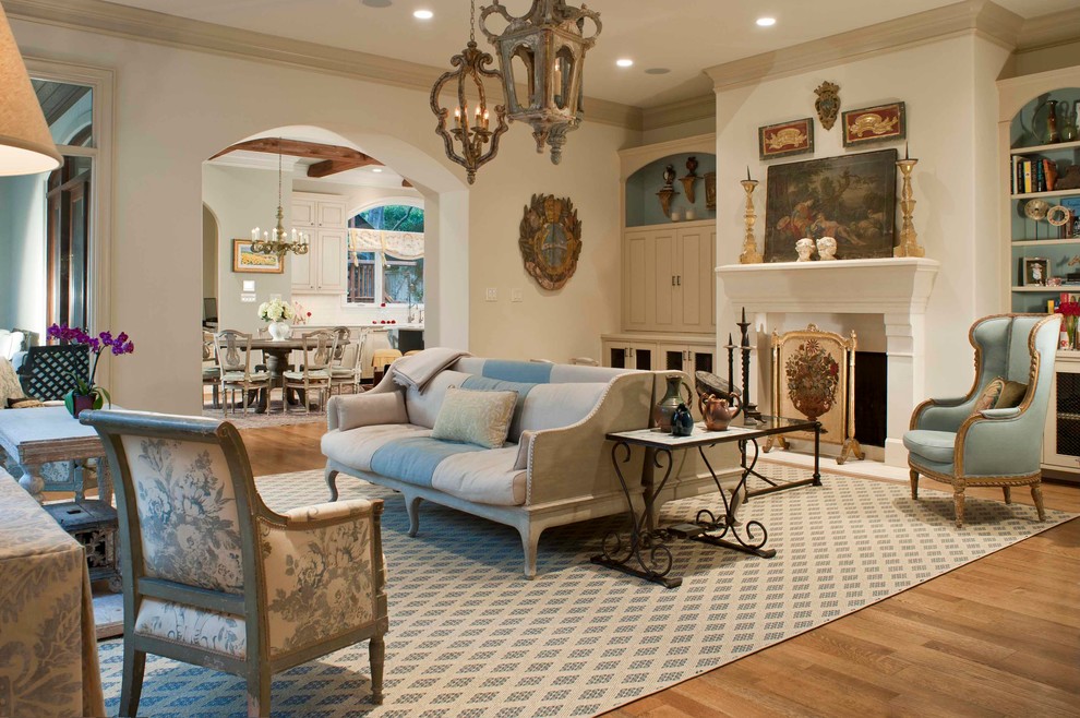 This is an example of a traditional formal open concept living room in Houston with white walls, medium hardwood floors and a standard fireplace.