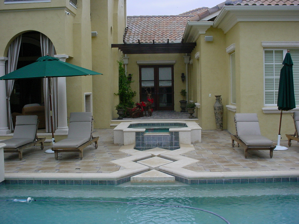 Photo of an expansive mediterranean backyard patio in Tampa with a water feature, natural stone pavers and a roof extension.