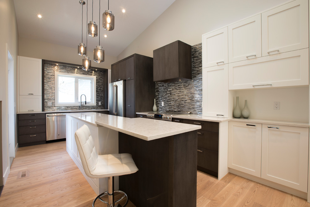 Eat-in kitchen - mid-sized transitional l-shaped light wood floor eat-in kitchen idea in Calgary with an undermount sink, shaker cabinets, white cabinets, quartzite countertops, gray backsplash, ceramic backsplash, stainless steel appliances and an island