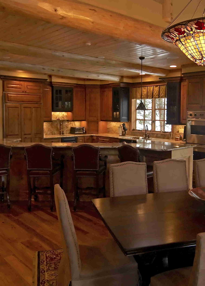 Inspiration for a large rustic l-shaped medium tone wood floor eat-in kitchen remodel in Denver with an undermount sink, raised-panel cabinets, brown cabinets, granite countertops, beige backsplash, stone slab backsplash, stainless steel appliances and an island