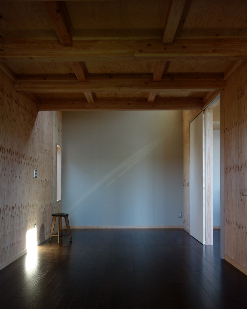 Modern inredning av ett litet hemmabibliotek, med grå väggar, plywoodgolv och brunt golv