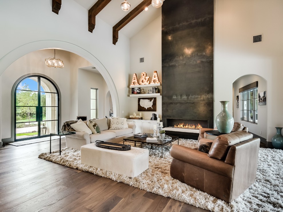 Mediterranean living room in Austin with white walls, light hardwood floors, a ribbon fireplace and beige floor.