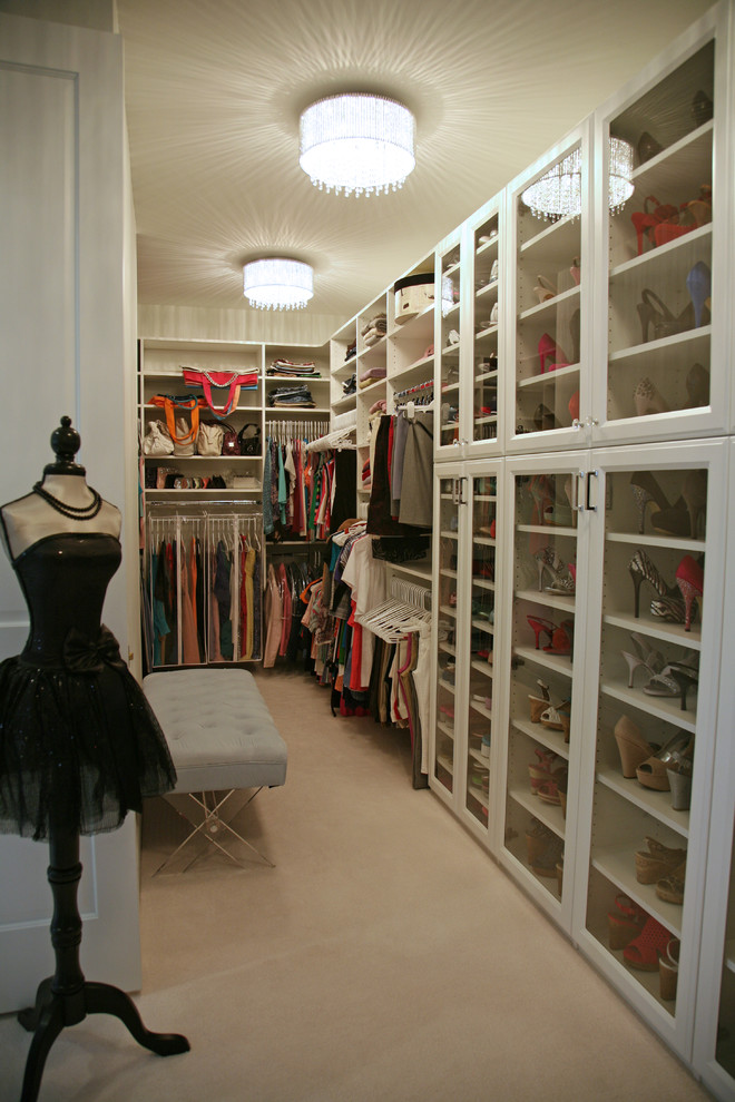 This is an example of a large traditional women's dressing room in Milwaukee with glass-front cabinets, white cabinets, carpet and white floor.